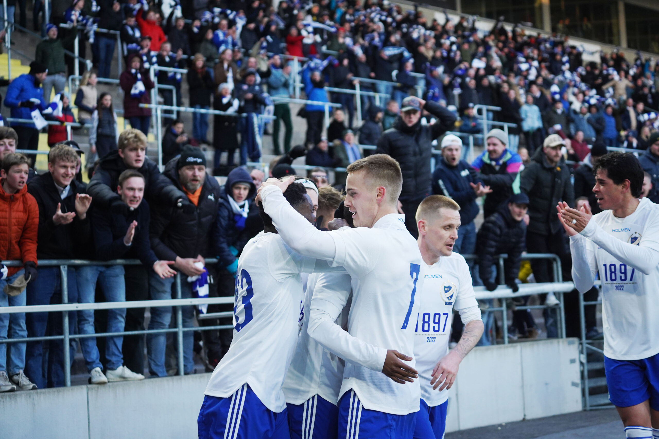 Fotbollsspelare kramas framför en läktare full med fans